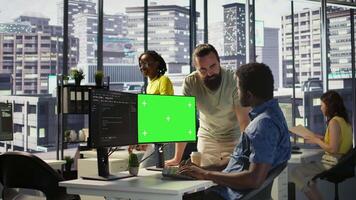 System administrator does software debugging on isolated screen PC, asking for help from coworker. Zoom in on admin fixing coding mistakes on chroma key computer, being assisted by colleague, camera B video