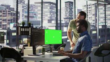 Developer using mockup PC, being assisted by colleague to fix applications issues, dealing with databases and server configuration. Team of IT workers using green screen computer, camera B video