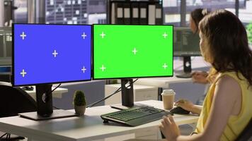 Employee using multi monitor isolated screen computer to analyze datasets, comparing accounting figures. Woman using chroma key PC to solve tasks for team project, camera A video