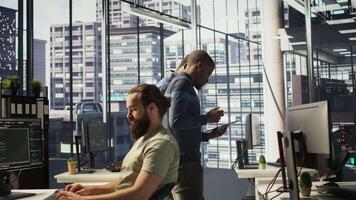 Managers evaluating work done by computer scientists in workspace doing software debugging. Management executives walking in office with tablet, checking code fixed by employees, camera B video