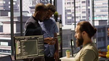 Machine learning infrastructure technicians using tablet to do checkup on algorithms that enable machines to learn from data. Coworkers in office training deep learning models using device video
