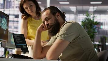 Exhausted developer caught asleep at desk by manager while developing AI machine learning company tech. Supervisor waking up tired sleeping employee while training predictive models, camera A video