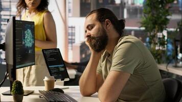Fatigued software engineer caught asleep at desk by manager while developing artificial intelligence tech. Team leader waking up lazy worker while training predictive models, camera A video