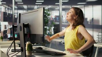 Worker sitting at office desk using computer during job shift, being interrupted by manager to receive info. Company employee in workspace doing tasks, listening to feedback from his boss, camera B video