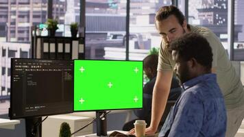 Admin doing software debugging on green screen PC, asking for help from coworker, checking errors in code. Worker fixing coding mistakes on mockup computer, being assisted by colleague, camera A video