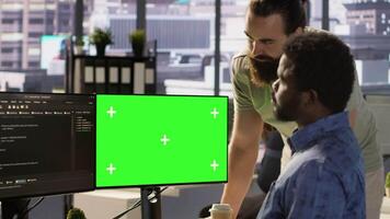 Developer using mockup PC, being assisted by colleague to fix applications issues, dealing with databases and server configuration. Team of IT workers using green screen computer, camera A video