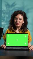 Vertical Media star reviews newly launched chroma key gaming laptop, comparing features with older models. Internet show host filming for social media, analyzing green screen notebook video