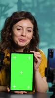 Vertical Content creator filming tech tutorial on how to repair damaged chroma key tablet. Technology guru in home studio teaching subscribers to install operating system on green screen device, camera A video