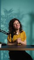 Vertical Smiling woman in studio using professional camera to record , greeting subscribers. Happy online star hosts q and a session with viewers, filming with advanced gear, camera B video