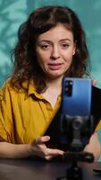 Vertical Tech expert presenting tablet in entry level low budget price range, filming from dimly lit home studio. Viral tech content creator reviewing digital device in front of online audience, camera A video