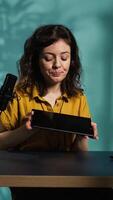 Vertical Tech expert presenting tablet in entry level low budget price range, filming from dimly lit home studio. Viral tech content creator reviewing digital device in front of online audience, camera B video