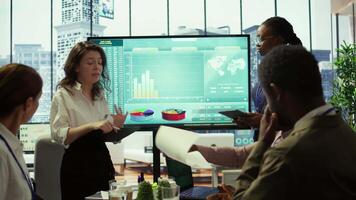 Coworkers engaging in a problem solving meeting at a corporation, using an interactive board to visualize data and develop solutions for complex business challenges. Analysis presentation. Camera B. video