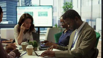 Shareholder examining infographics and resource allocation on tablet, gathering with associates for a strategy session. Utilizing data analytics to develop innovative solutions for growth. Camera B. video