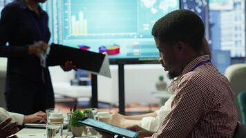 Diverse work team collaborating on project management tasks, utilizing smart technology and detailed analytics to optimize resource allocation and ensure enterprise objectives. Camera A. video
