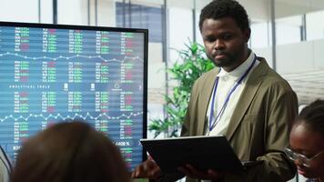 attività commerciale associati condivisione idee nel un' aziendale riunione incontro, utilizzando interattivo tavole per presente dettagliato progetto rapporti e allineare su chiave prestazione indicatori e obiettivi. telecamera un. video