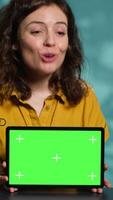 Vertical Happy internet star being sponsored by partnering brand to do mockup tablet unboxing content. Smiling tech specialist does influencer marketing, presenting green screen device, camera A video