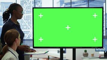 Diverse work team discusses corporate strategies with a big green screen, meeting in high end boardroom to examine market trends. Sharing new ideas for business growth and expansion. Camera A. video