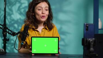 Happy internet star being sponsored by partnering brand to do mockup tablet unboxing content. Smiling tech specialist does influencer marketing, presenting green screen device, camera A video