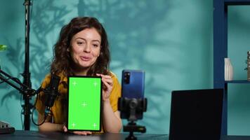 Content creator filming tech tutorial on how to repair damaged chroma key tablet. Technology guru in home studio teaching subscribers to install operating system on green screen device, camera A video