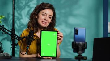 Happy technology expert at home holding newly launched green screen tablet in hand, presenting camera and screen specs. Jolly media star doing chroma key digital device review for viewers, camera A video