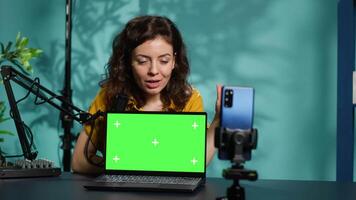 Influencer in home studio using recording tech to capture live broadcast, reviewing chroma key laptop. Online show host filming electronics haul, presenting green screen notebook for viewers, camera A video