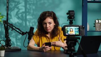 Streamer doing live broadcast, reading juicy text messages from mobile phone screen. Influencer commenting about social media posts on cellphone, talking with viewers, camera A video