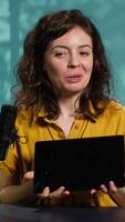 Vertical Tech guru presenting tablet from brand sponsoring , urging viewers to purchase it. Technology expert does influencer marketing by advertising digital device to audience, camera A video