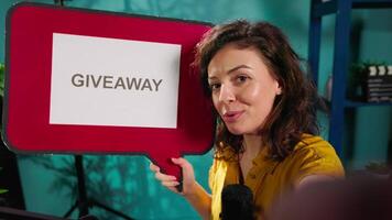 Media star holding empty copy space sign using handheld camera to film giveaway. POV shot of upbeat woman offering prizes during internet contest, recording with professional microphone video
