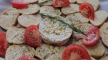Baked Camembert sprinkle with Provencal herbs on a baking sheet and foil cheese tomatoes and pieces of bread croutons prepare for baking video