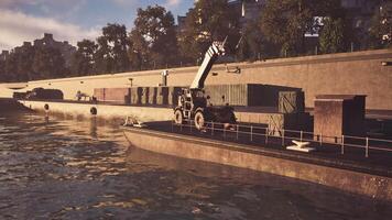 Tractor loading cargo containers onto a barge at a riverside dock during sunset video