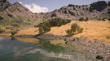 Serene lakeside view with rocky mountains in the background during daylight video