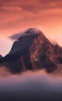 A mountain is covered in clouds at sunset photo