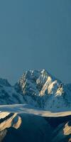 A snow covered mountain range with a lone snow covered tree photo