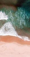 An aerial view of a beach with waves and a person on a surfboard photo