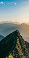 A mountain top with a path leading down to the valley photo