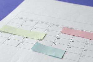Calendar of the month and several colored adhesive notes to highlight the activities to be done. Copy space. Concept of time organization and achievement of objectives. photo