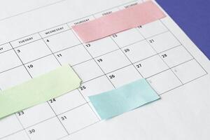 Calendar of the month and several colored adhesive notes to highlight the activities to be done. Copy space. Concept of time organization and achievement of objectives. photo
