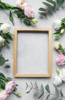 Delicate flowers arranged around an empty wooden frame on a textured surface photo