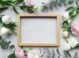 Delicate flowers arranged around an empty wooden frame on a textured surface photo