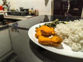 A delicious plate featuring golden nuggets, fluffy scrambled eggs, and crispy fried spinach, served with white rice. Perfect for a balanced meal with a variety of textures and flavors photo