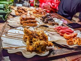 Traditional Indonesian angkringan street food stall with assorted grilled skewers, vibrant night market scene. Perfect for capturing the essence of local cuisine and culture photo