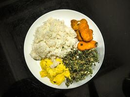 A delicious plate featuring golden nuggets, fluffy scrambled eggs, and crispy fried spinach, served with white rice. Perfect for a balanced meal with a variety of textures and flavors photo