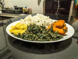 A delicious plate featuring golden nuggets, fluffy scrambled eggs, and crispy fried spinach, served with white rice. Perfect for a balanced meal with a variety of textures and flavors photo