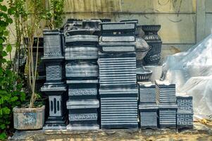 Stacked black plastic crates and plant pots against a wall, outdoor storage concept, space for text photo