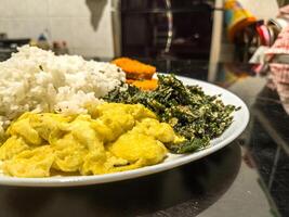 A delightful plate featuring golden nuggets, fluffy scrambled eggs, and crispy fried spinach, served with white rice. Perfect for a balanced meal with a variety of textures and flavors photo