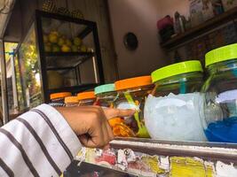 Customer selecting colorful items in jars at a local market stall, highlighting the vibrant and diverse offerings of street commerce photo
