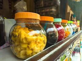 Assorted beverage toppings in clear jars with vibrant lids lined up, offering a visual feast of textures and colors for sweet treats. Perfect for cafes and beverage shops photo