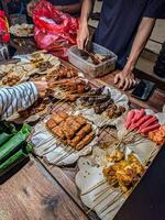 Traditional Indonesian street food stall angkringan with various skewered snacks and local delicacies. Capturing the vibrant atmosphere of night market dining photo