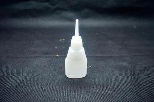 Close up of Cyanoacrylate Ethyl adhesive bottle on dark textured surface, essential for quick repairs photo