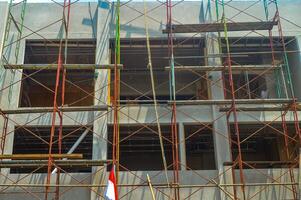 Urban construction site with intricate scaffolding structure against incomplete building facade photo